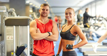 Happy male and female standing in a gym after tracking body composition with a BMI scale